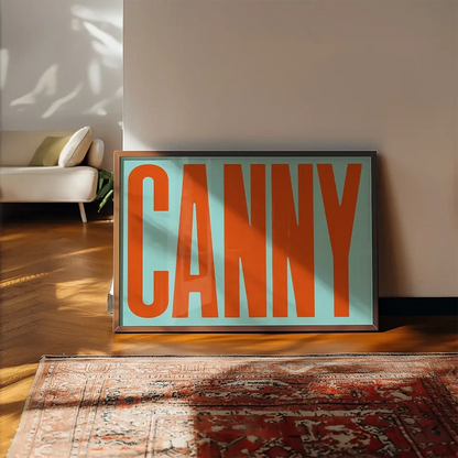 Canny Typography Quote Print - Orange framed, leaning on a wooden floor beside a rug