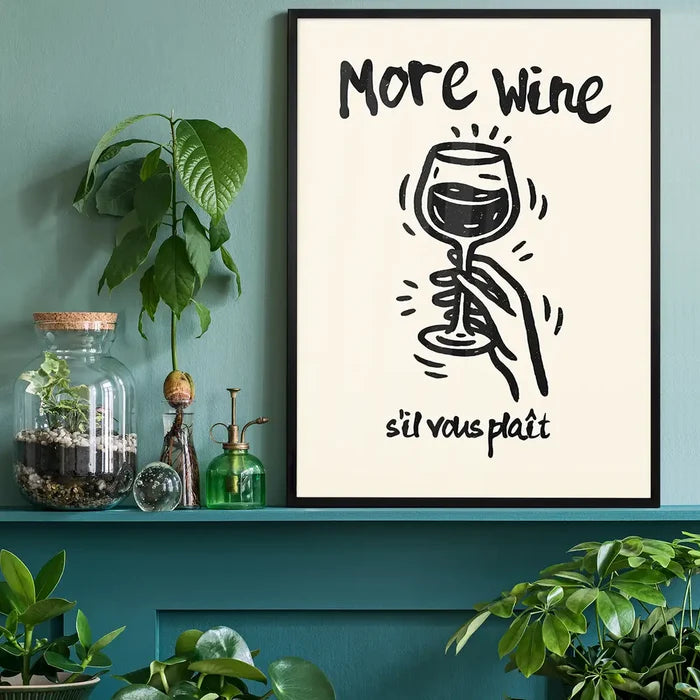 More Wine s'il vous plaît Quote Print black framed on a living room shelf