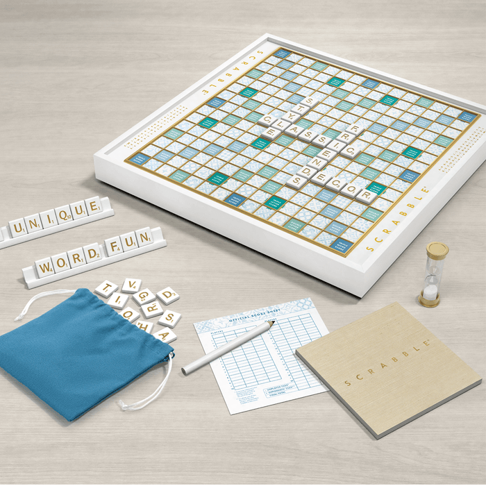 Scrabble board game set with tiles, bag, and score sheet on a light surface