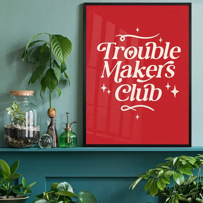 Trouble Makers Club Quote Print black framed on a living room shelf