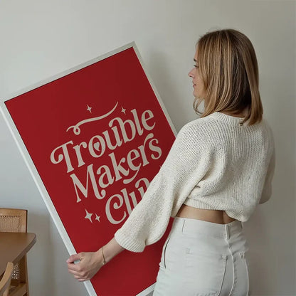 Trouble Makers Club Quote Print held up against a living room wall