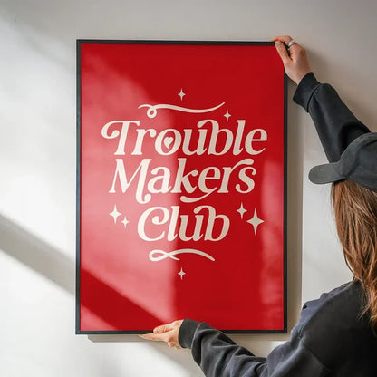 Trouble Makers Club Quote Print being hung on a wall in a black frame
